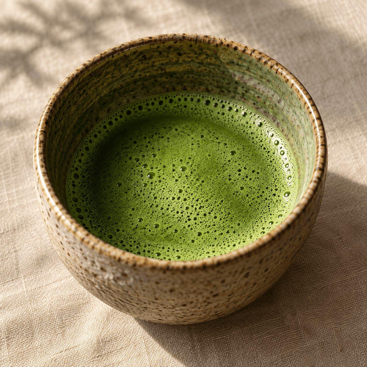 A ceramic bowl of freshly whisked matcha with delicate green foam